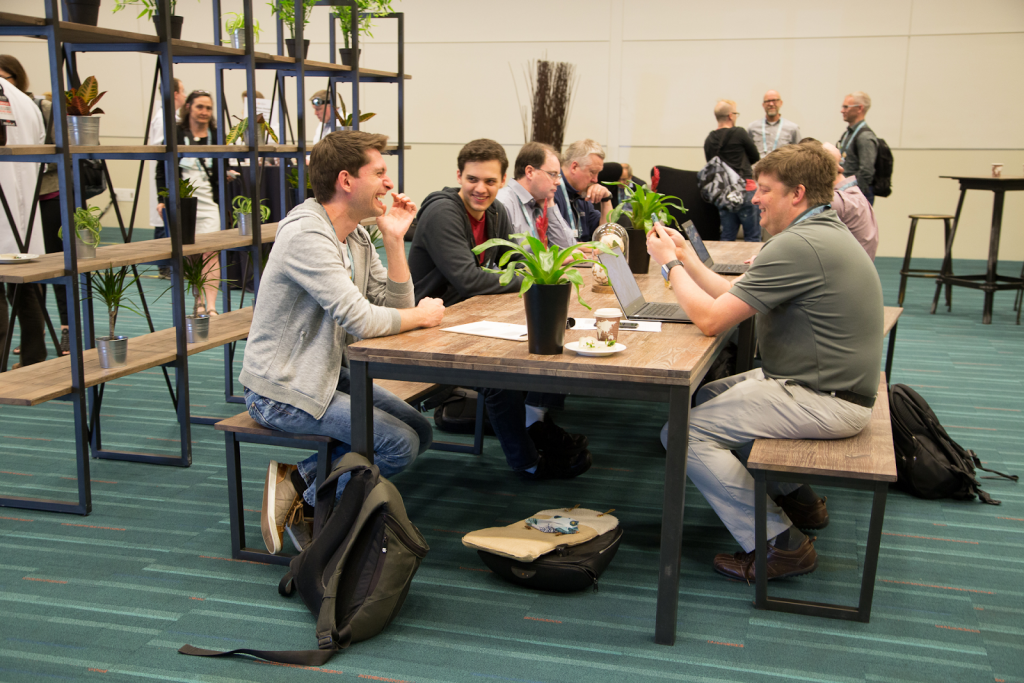 Image of people gathered around an office table laughing and smiling. 