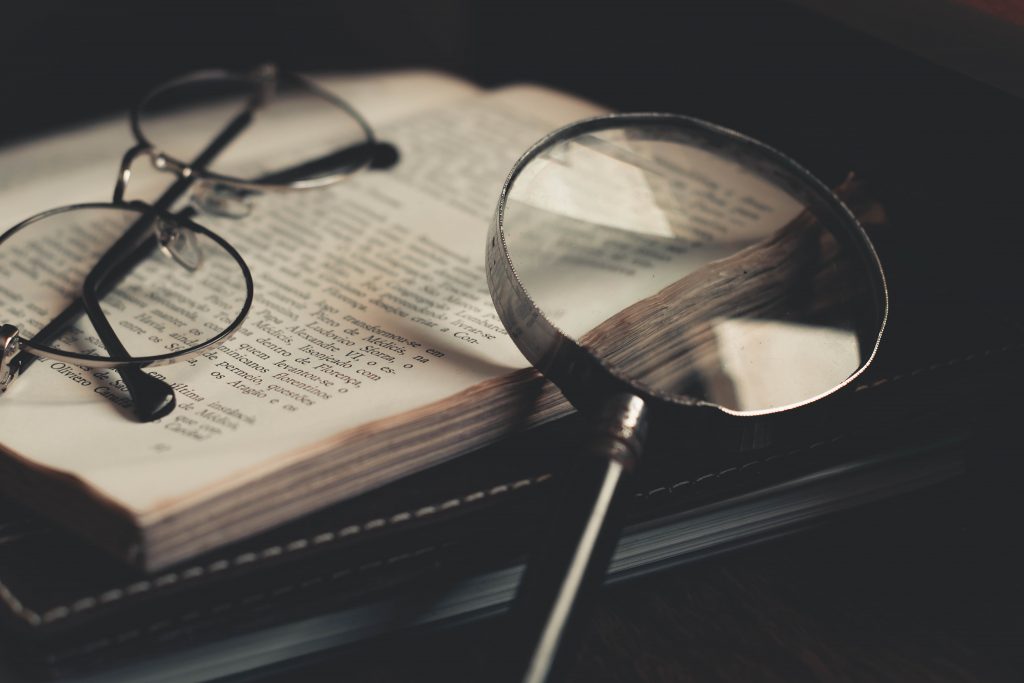 An image of reading glasses and magnifying glass placed on a book to represent specific and specialized knowledge. 